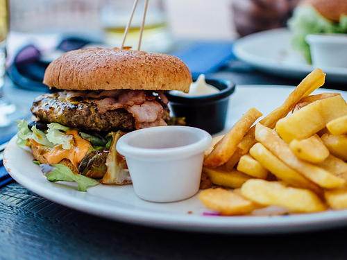 Hamburguesa con papas fritas servida en plato, cocina rápida